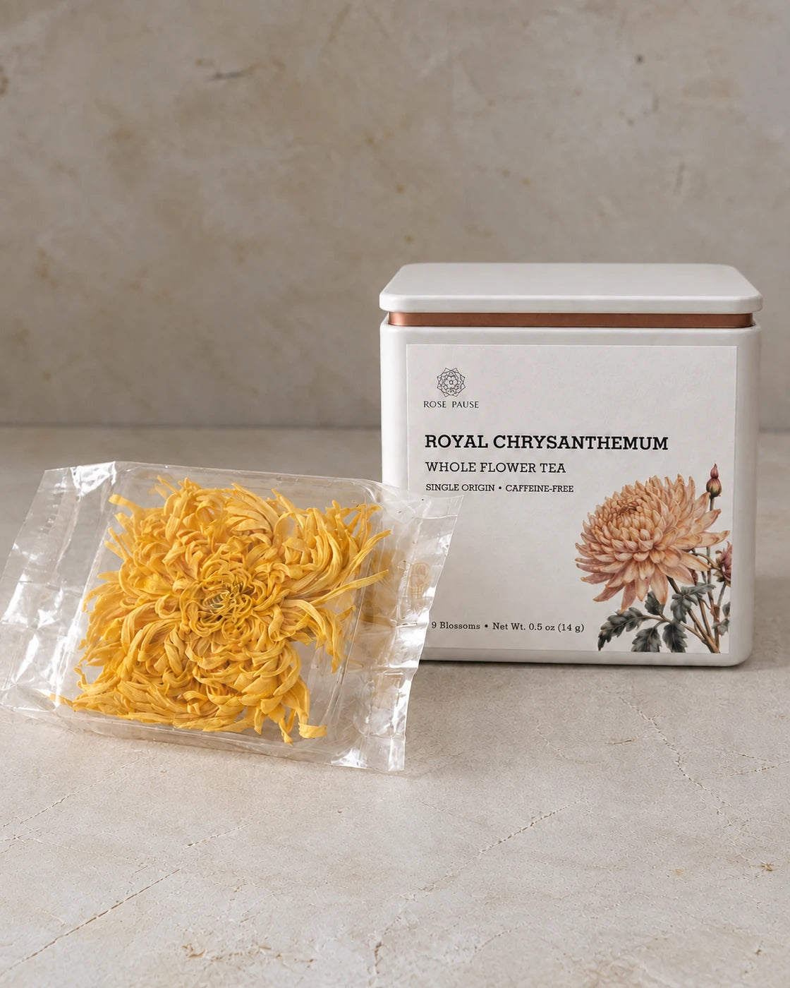 Rose Pause Royal Chrysanthemum whole flower tea tin beside an individually wrapped dried golden blossom.