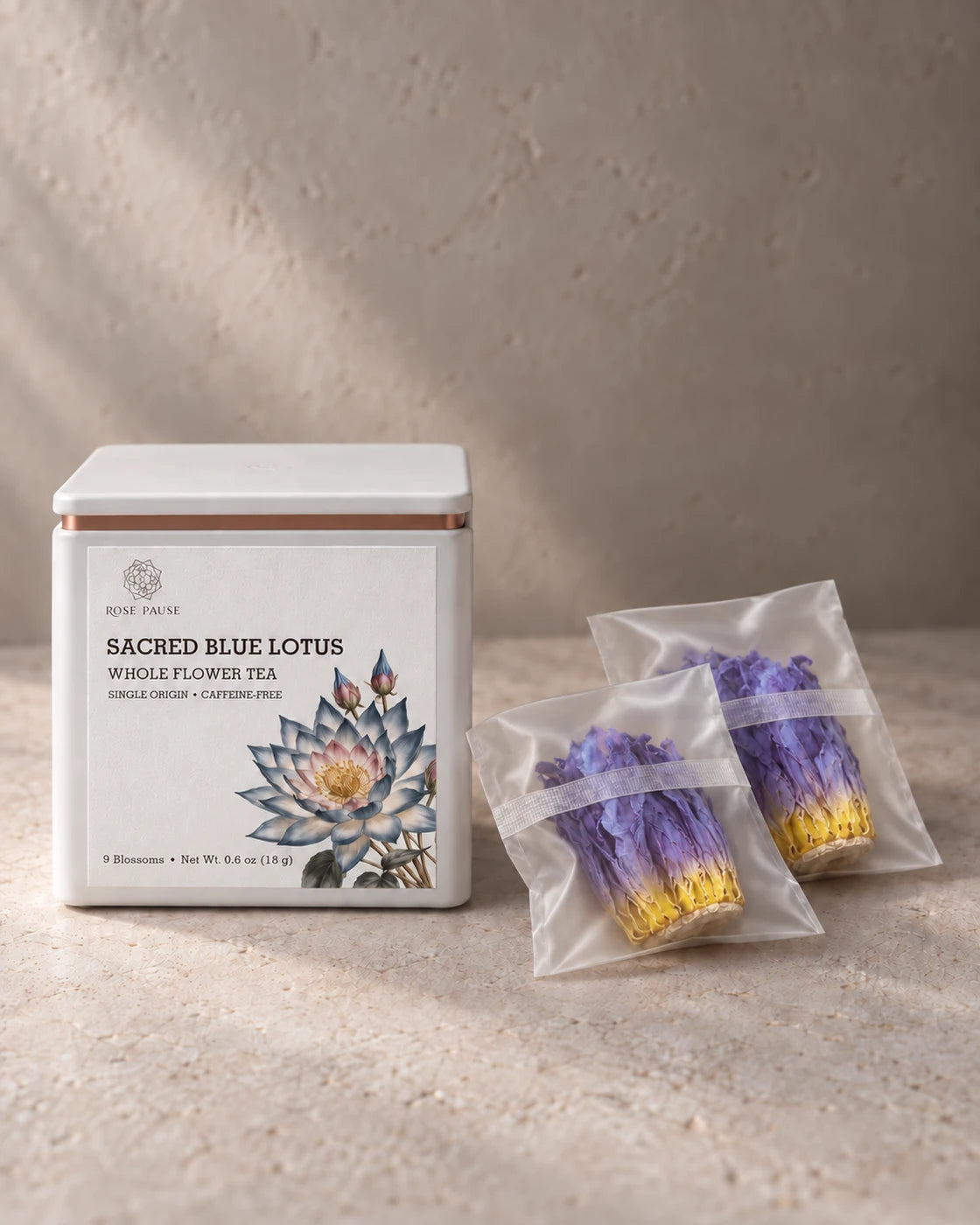 Rose Pause Sacred Blue Lotus tea tin beside two individually wrapped dried whole flowers.