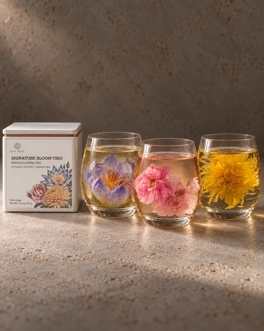 Rose Pause Signature Bloom Trio tea tin beside three glasses of rose, chrysanthemum and blue lotus tea.